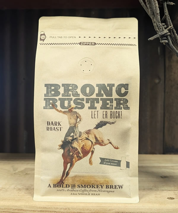 Bag of Bronc Buster dark roast whole bean coffee with smoky, chocolate, and pecan notes